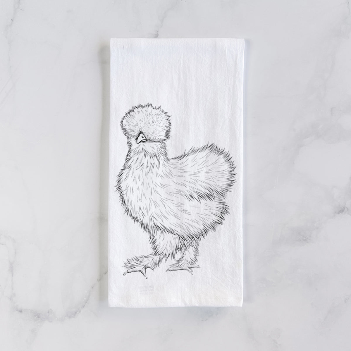 White cotton tea towel laid flat on marble, printed with a black ink illustration of a fluffy silkie chicken.