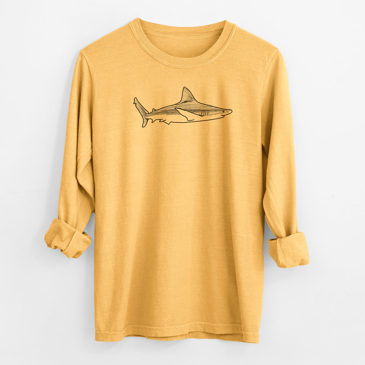 Golden wheat yellow Comfort Colors long sleeve shirt laid flat with the cuffs rolled, printed with a black ink illustration of a silvertip shark swimming in profile.