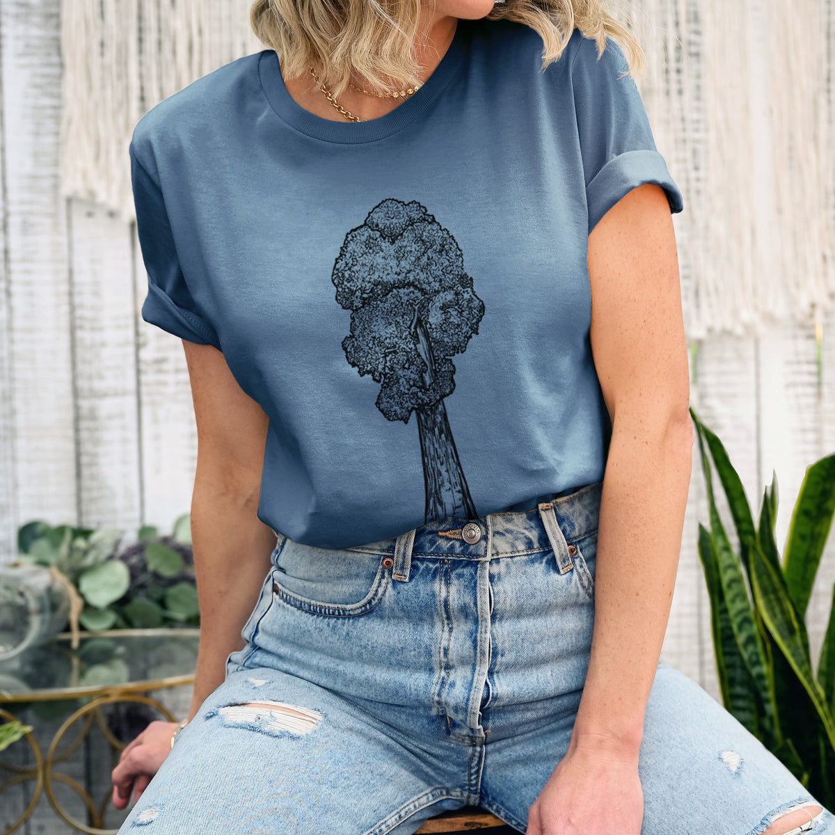 Woman wearing a steel blue lightweight cotton t-shirt printed with a black ink illustration of a single giant sequoia tree.