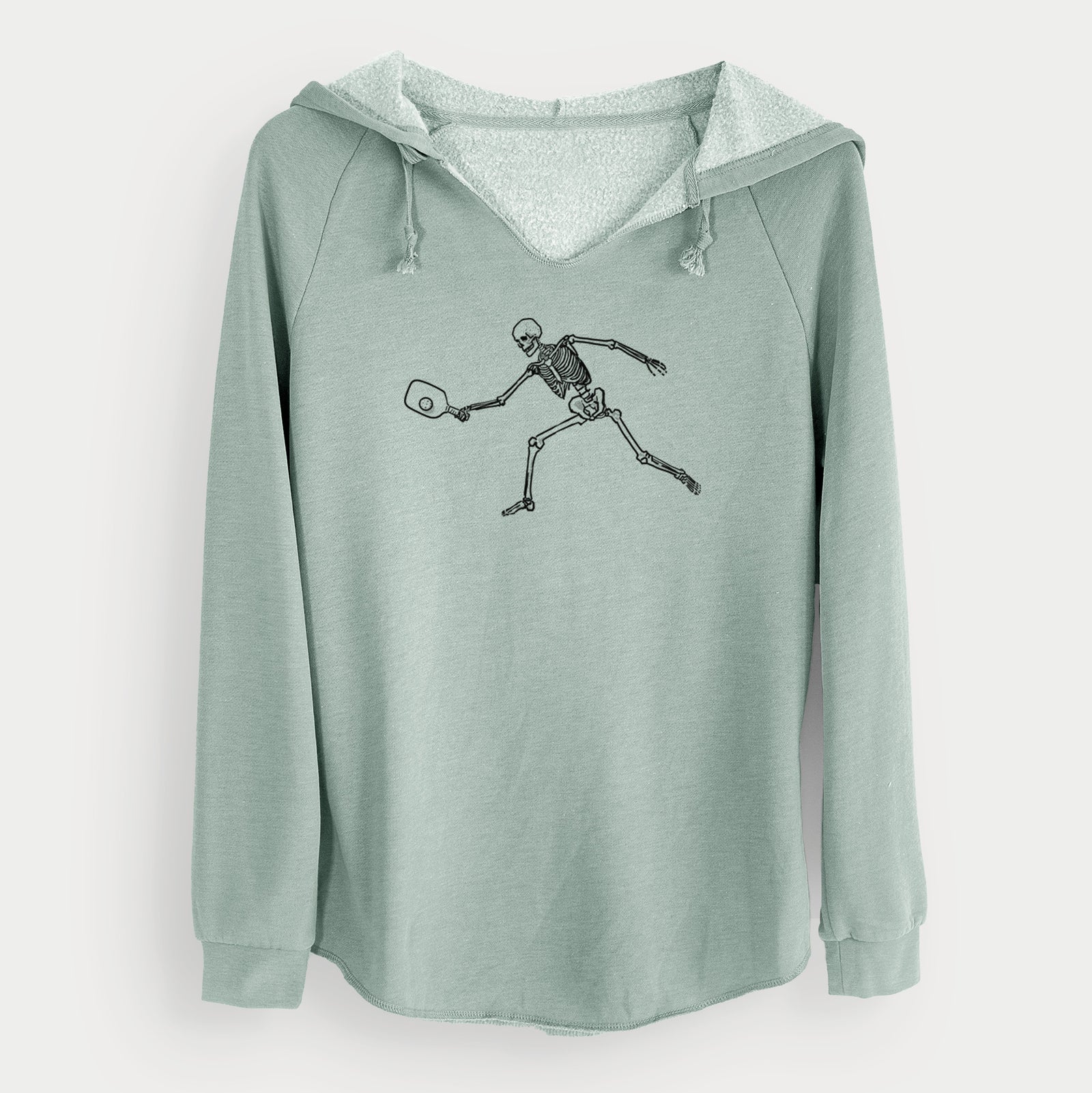 Sage green women's Cali Wave hooded sweatshirt laid flat, printed with a black ink skeleton lunging to hit a pickleball with a paddle.