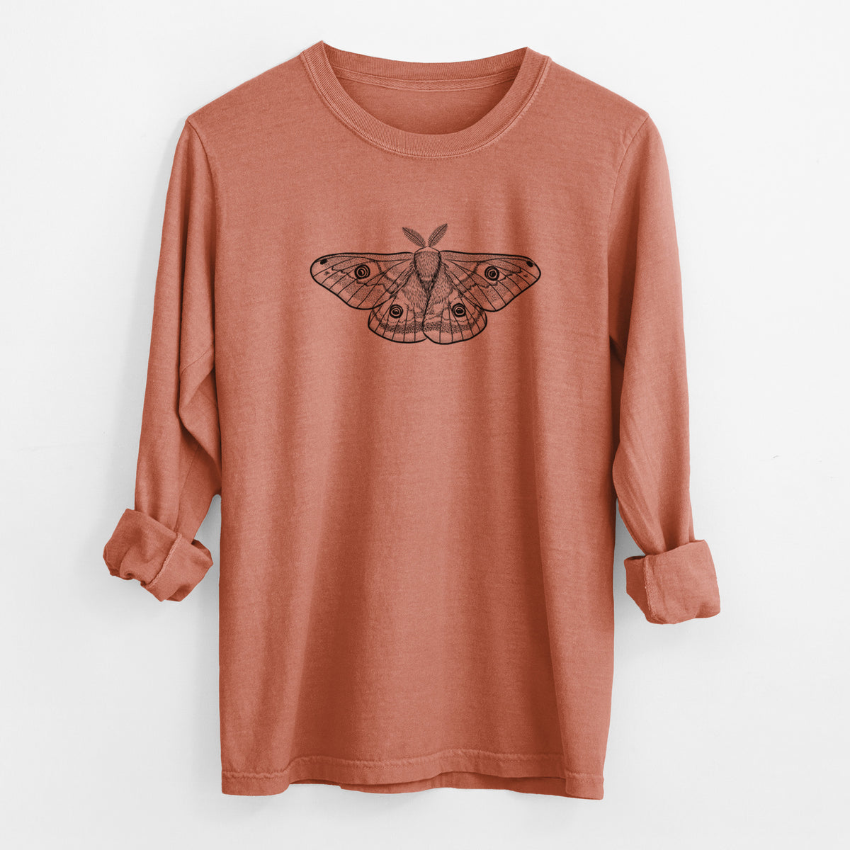 Yam burnt orange Comfort Colors long sleeve shirt laid flat with the cuffs rolled, printed with a detailed black ink illustration of a small emperor moth with eyespots on its wings.