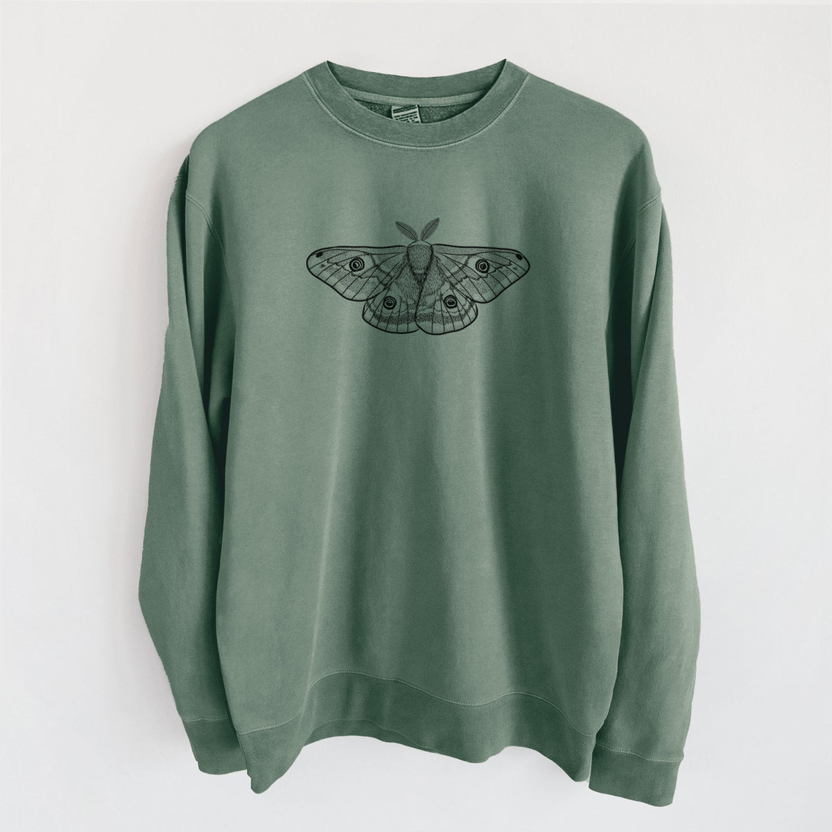 Alpine green pigment dyed crewneck sweatshirt laid flat, printed with a detailed black ink illustration of a small emperor moth with eyespots on its wings.
