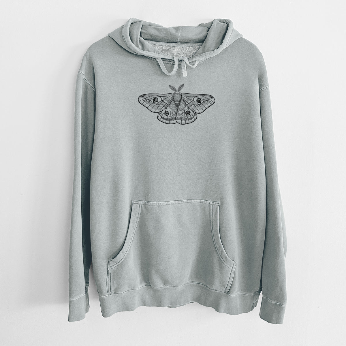 Sage green pigment dyed hoodie laid flat, printed with a detailed black ink illustration of a small emperor moth with eyespots on its wings.