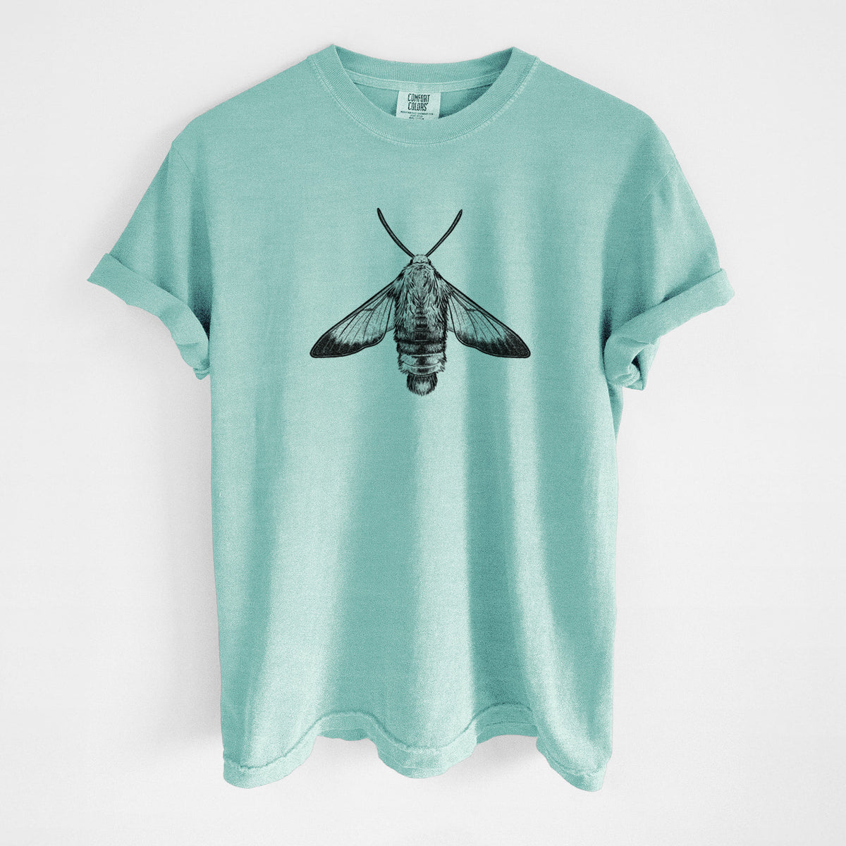 Chalky mint Comfort Colors t-shirt laid flat, printed with a detailed black ink illustration of a snowberry clearwing moth, seen from above.