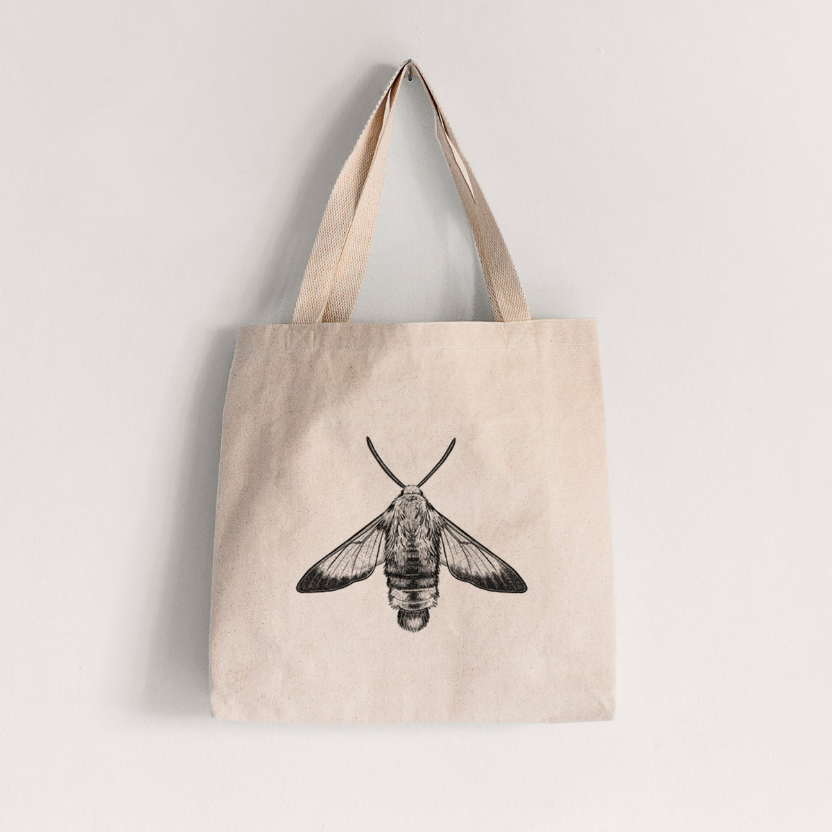 Natural canvas tote bag printed with a detailed black ink illustration of a snowberry clearwing moth, seen from above.