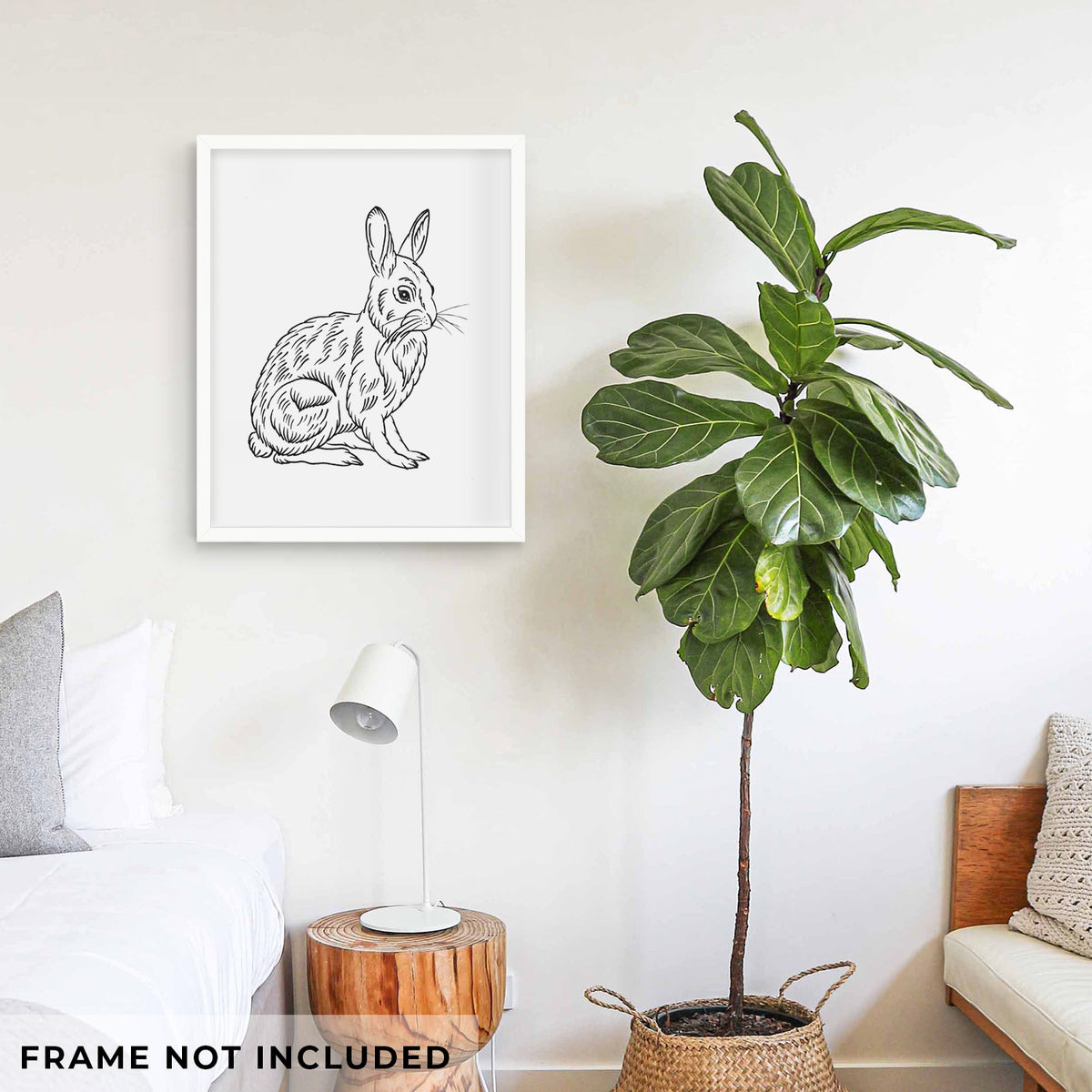 Art print of a detailed black ink illustration of a snowshoe hare sitting upright, shown framed on a living room wall beside a potted plant. Frame not included.