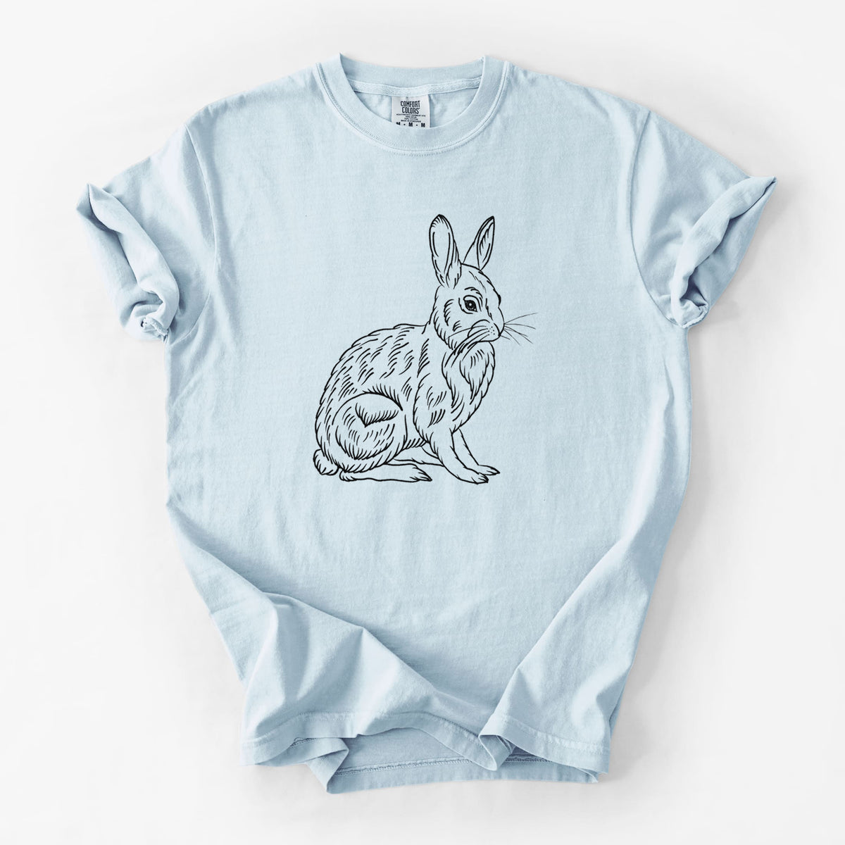Chambray blue Comfort Colors t-shirt laid flat, printed with a detailed black ink illustration of a snowshoe hare sitting upright.