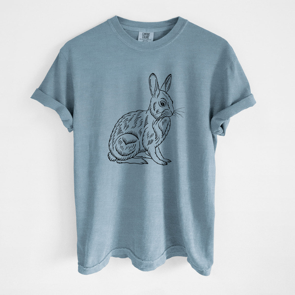 Steel blue Comfort Colors t-shirt laid flat, printed with a detailed black ink illustration of a snowshoe hare sitting upright.