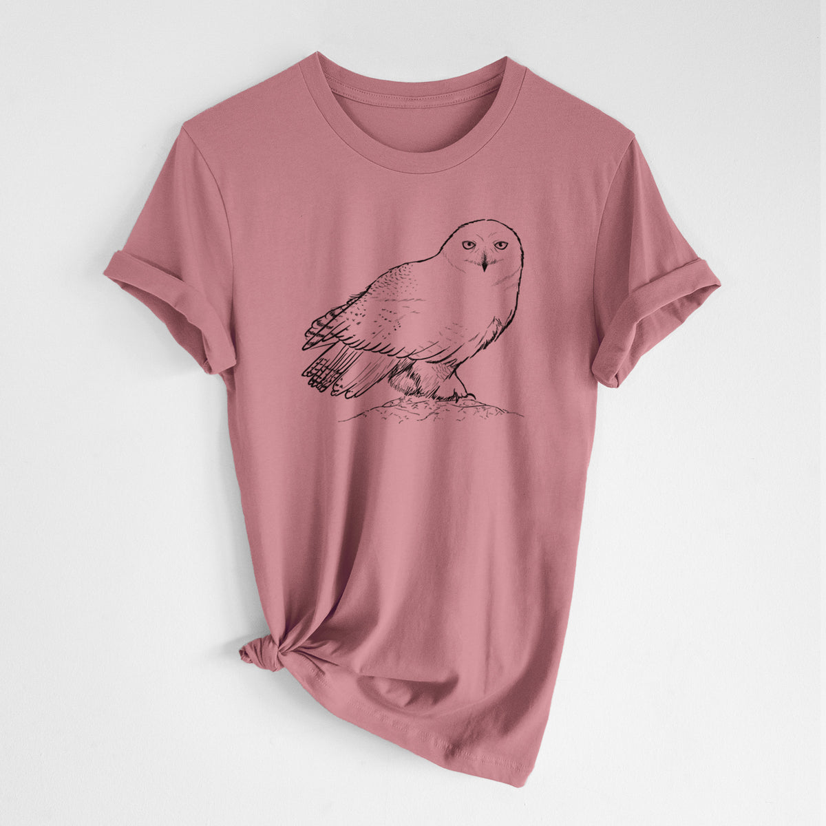 Mauve pink lightweight cotton t-shirt laid flat with the sleeves rolled, printed with a detailed black ink illustration of a snowy owl perched on a snowy mound.
