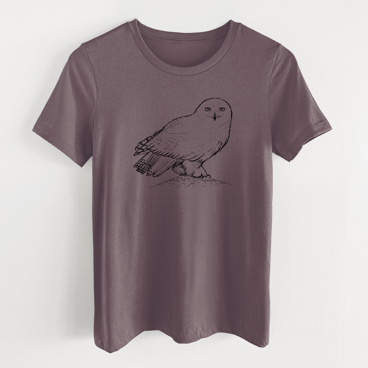 Purple storm women's relaxed fit cotton t-shirt laid flat, printed with a detailed black ink illustration of a snowy owl perched on a snowy mound.