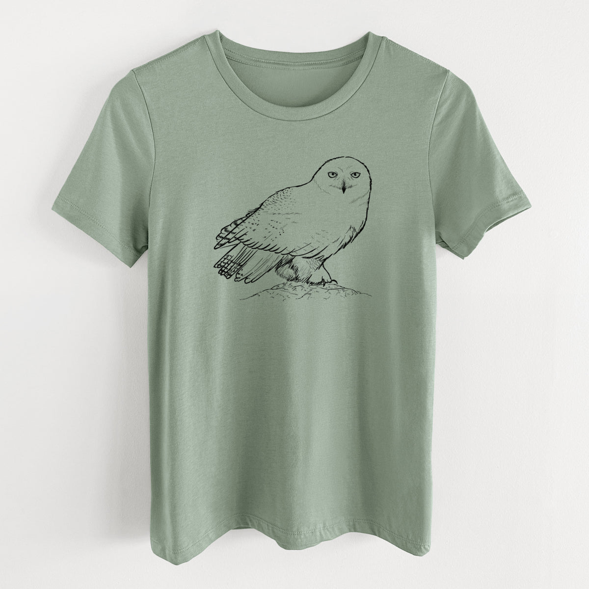 Sage green women's relaxed fit cotton t-shirt laid flat, printed with a detailed black ink illustration of a snowy owl perched on a snowy mound.