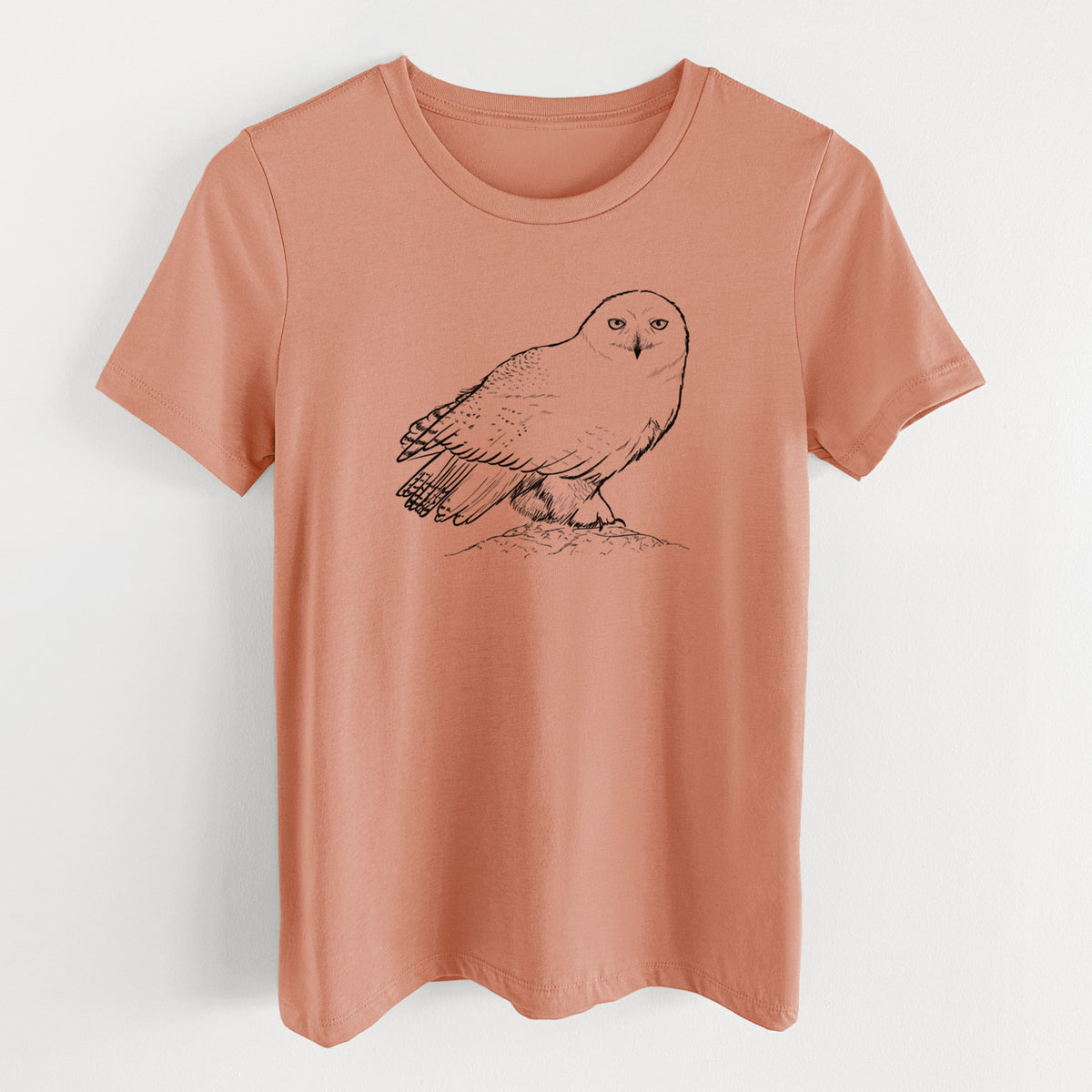 Terracotta orange women's relaxed fit cotton t-shirt laid flat, printed with a detailed black ink illustration of a snowy owl perched on a snowy mound.