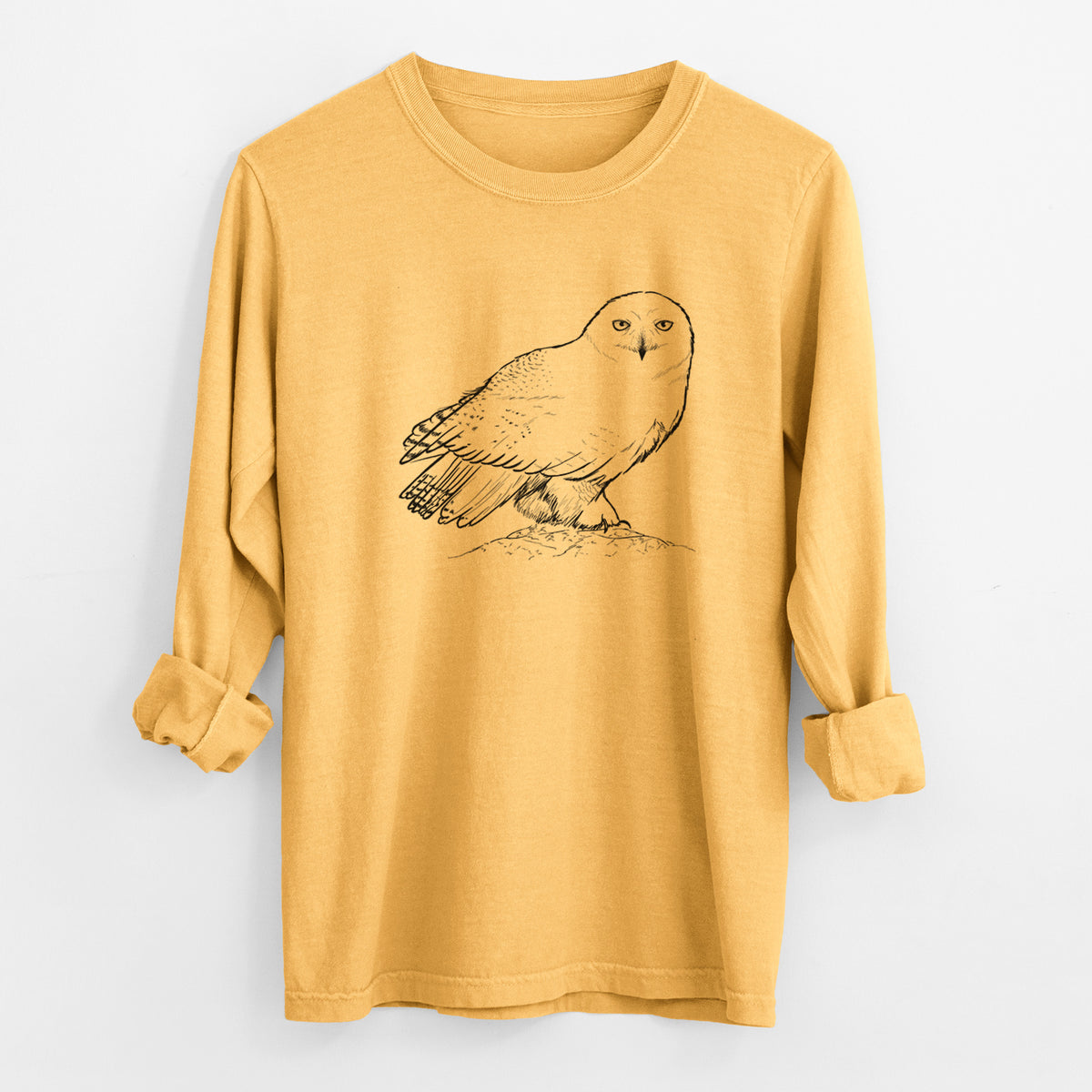 Golden wheat yellow Comfort Colors long sleeve shirt laid flat with the cuffs rolled, printed with a detailed black ink illustration of a snowy owl perched on a snowy mound.