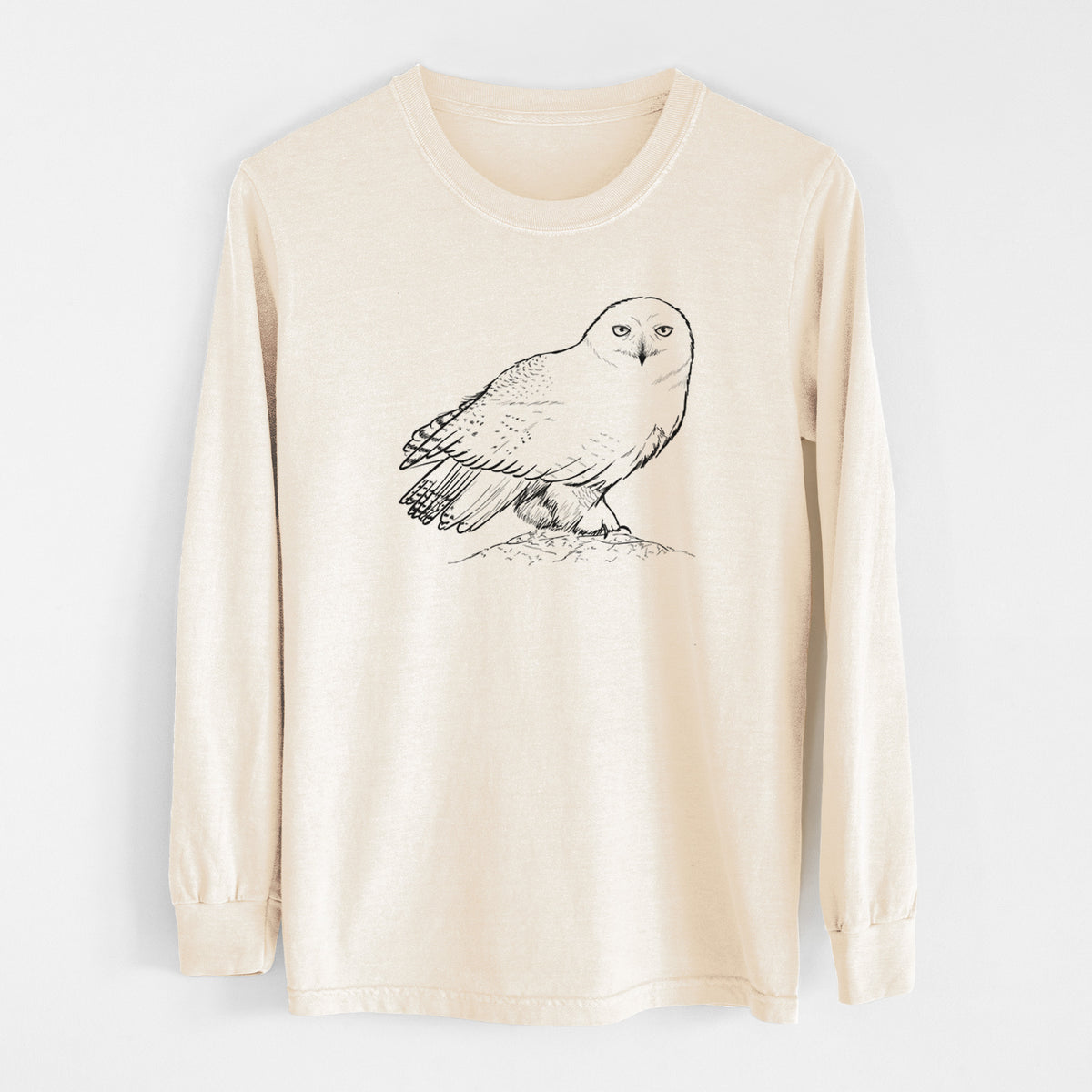 Ivory Comfort Colors long sleeve shirt laid flat, printed with a detailed black ink illustration of a snowy owl perched on a snowy mound.
