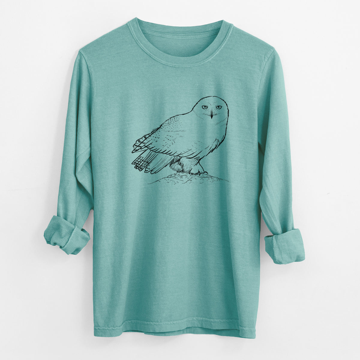 Reef green Comfort Colors long sleeve shirt laid flat with the cuffs rolled, printed with a detailed black ink illustration of a snowy owl perched on a snowy mound.