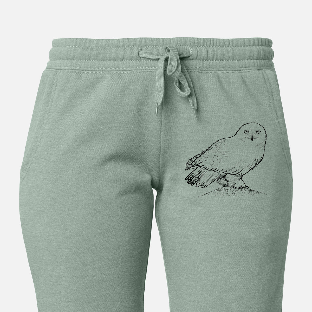 Front of sage green Cali Wave sweatpants, printed with a detailed black ink illustration of a snowy owl perched on a snowy mound on the leg.