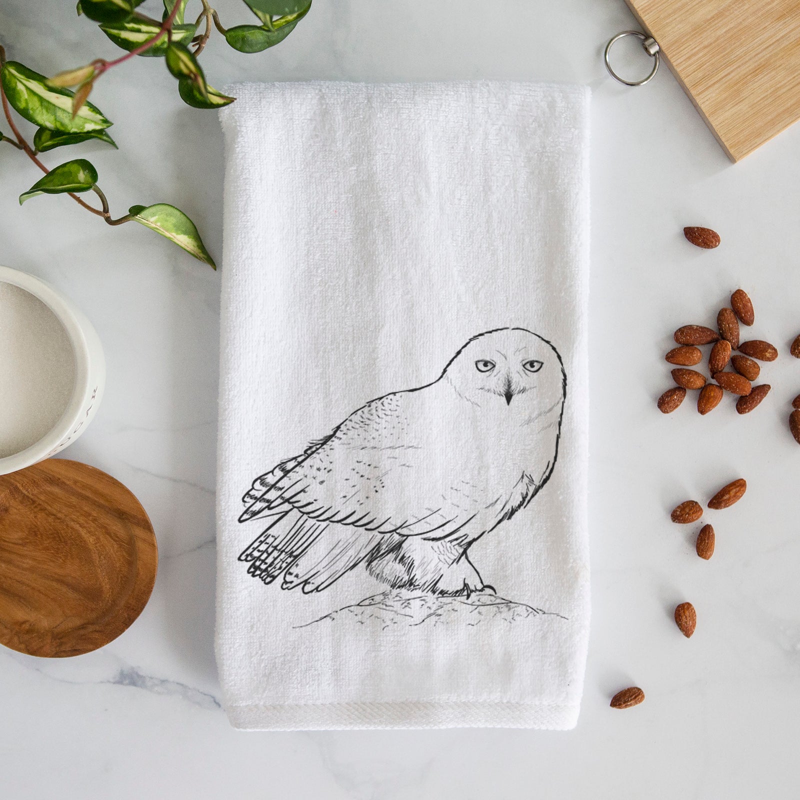 White hand towel printed with a detailed black ink illustration of a snowy owl perched on a snowy mound.