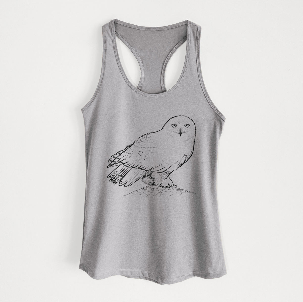 Heather grey women's racerback tank top laid flat, printed with a detailed black ink illustration of a snowy owl perched on a snowy mound.