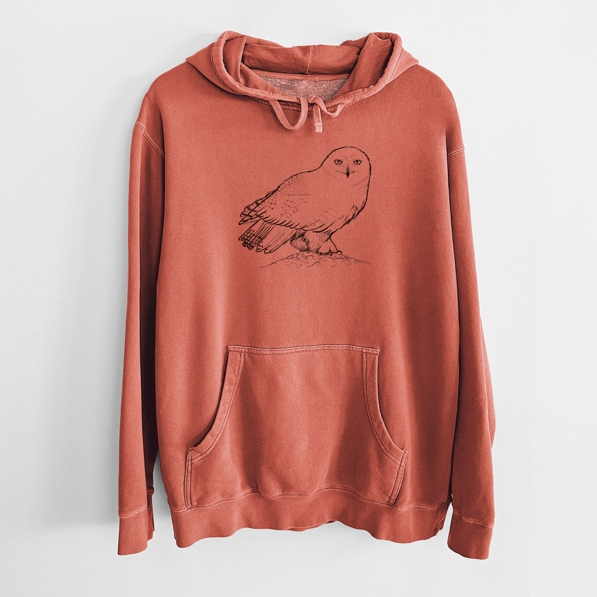 Amber orange pigment dyed hoodie laid flat, printed with a detailed black ink illustration of a snowy owl perched on a snowy mound.