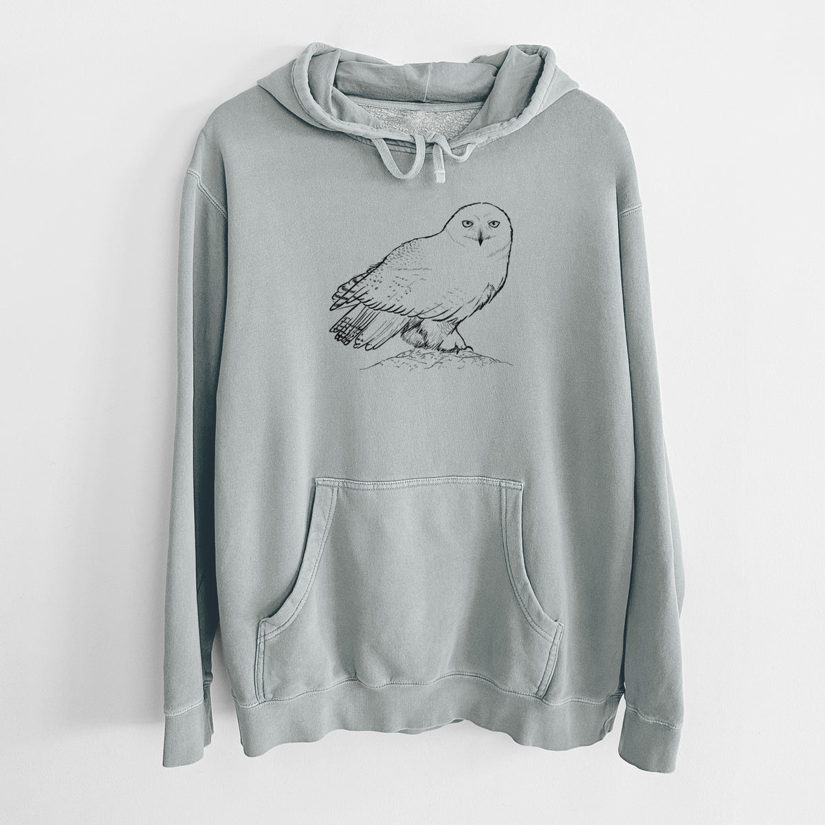 Sage green pigment dyed hoodie laid flat, printed with a detailed black ink illustration of a snowy owl perched on a snowy mound.