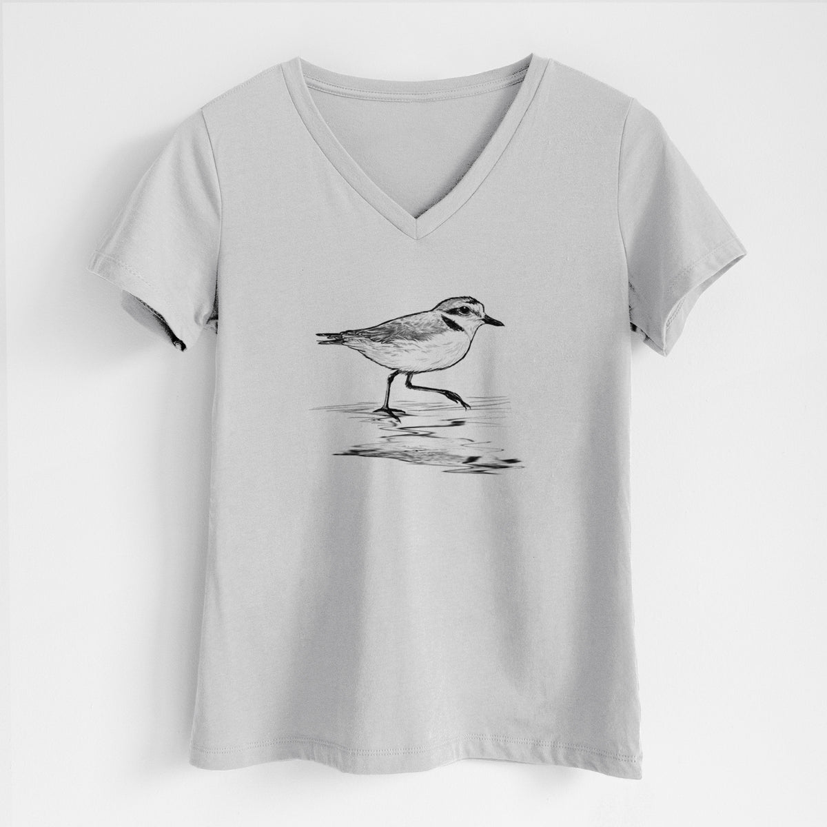 Lunar grey women's relaxed fit cotton V-neck t-shirt laid flat, printed with a black ink sketch of a snowy plover running along the wet shoreline.