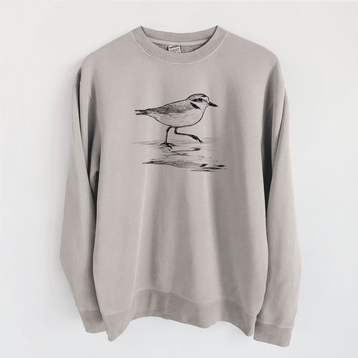 Cement grey pigment dyed crewneck sweatshirt laid flat, printed with a black ink sketch of a snowy plover running along the wet shoreline.
