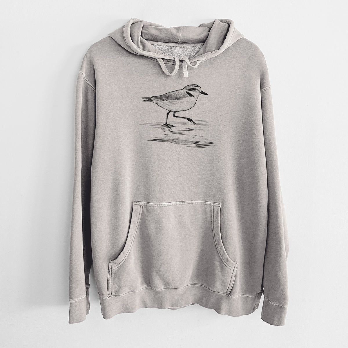 Cement grey pigment dyed hoodie laid flat, printed with a black ink sketch of a snowy plover running along the wet shoreline.