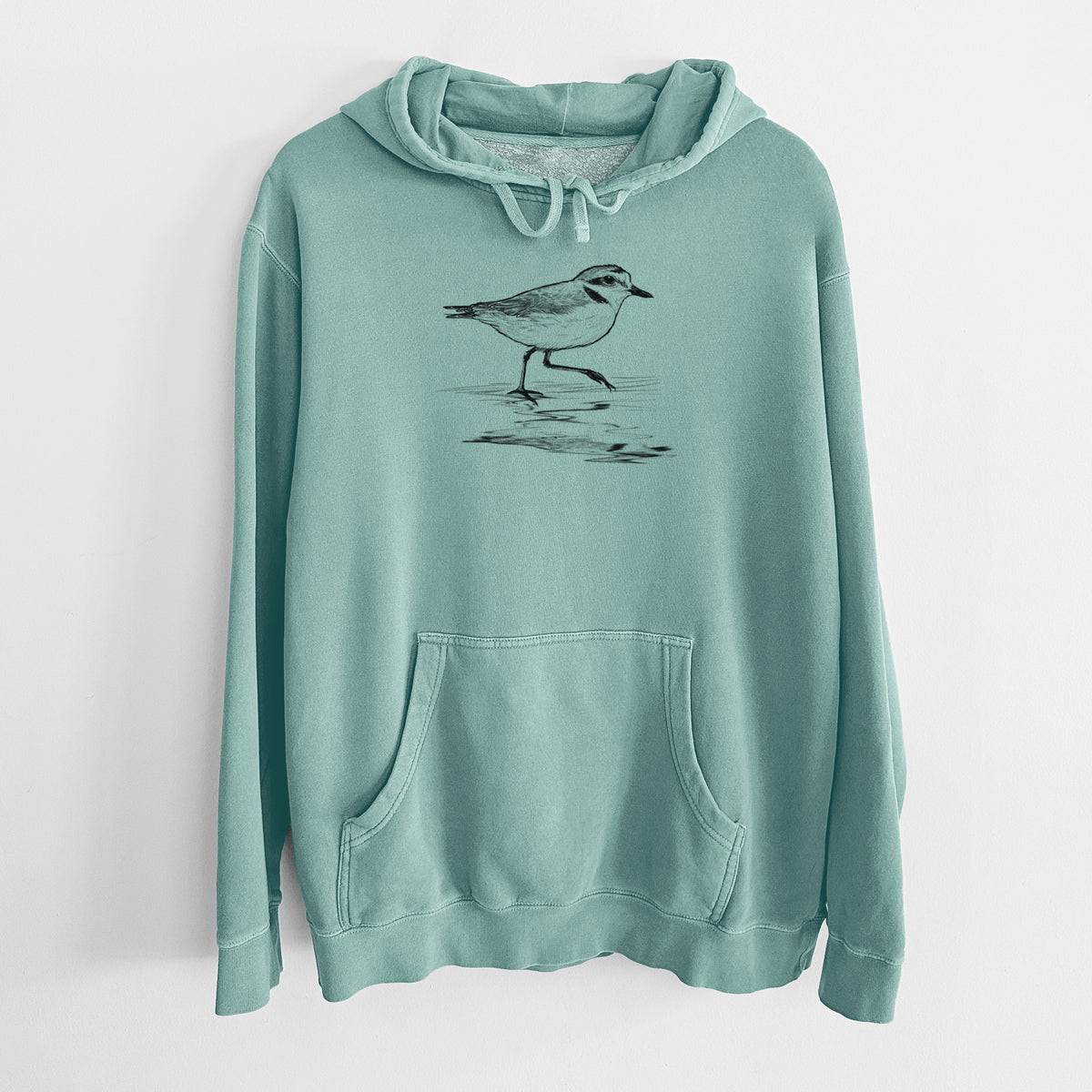 Mint green pigment dyed hoodie laid flat, printed with a black ink sketch of a snowy plover running along the wet shoreline.