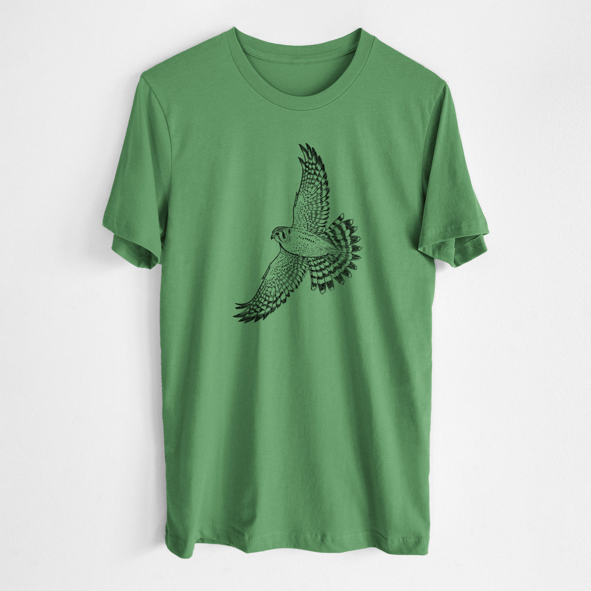 Leaf green lightweight cotton t-shirt laid flat, printed with a detailed black ink illustration of an American kestrel in flight with its wings raised.