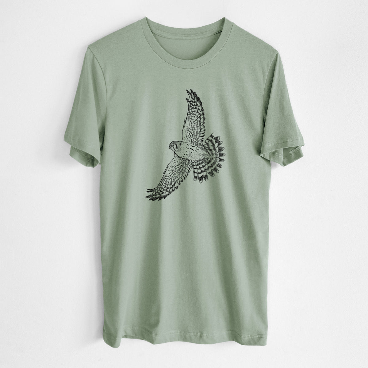 Sage green lightweight cotton t-shirt laid flat, printed with a detailed black ink illustration of an American kestrel in flight with its wings raised.