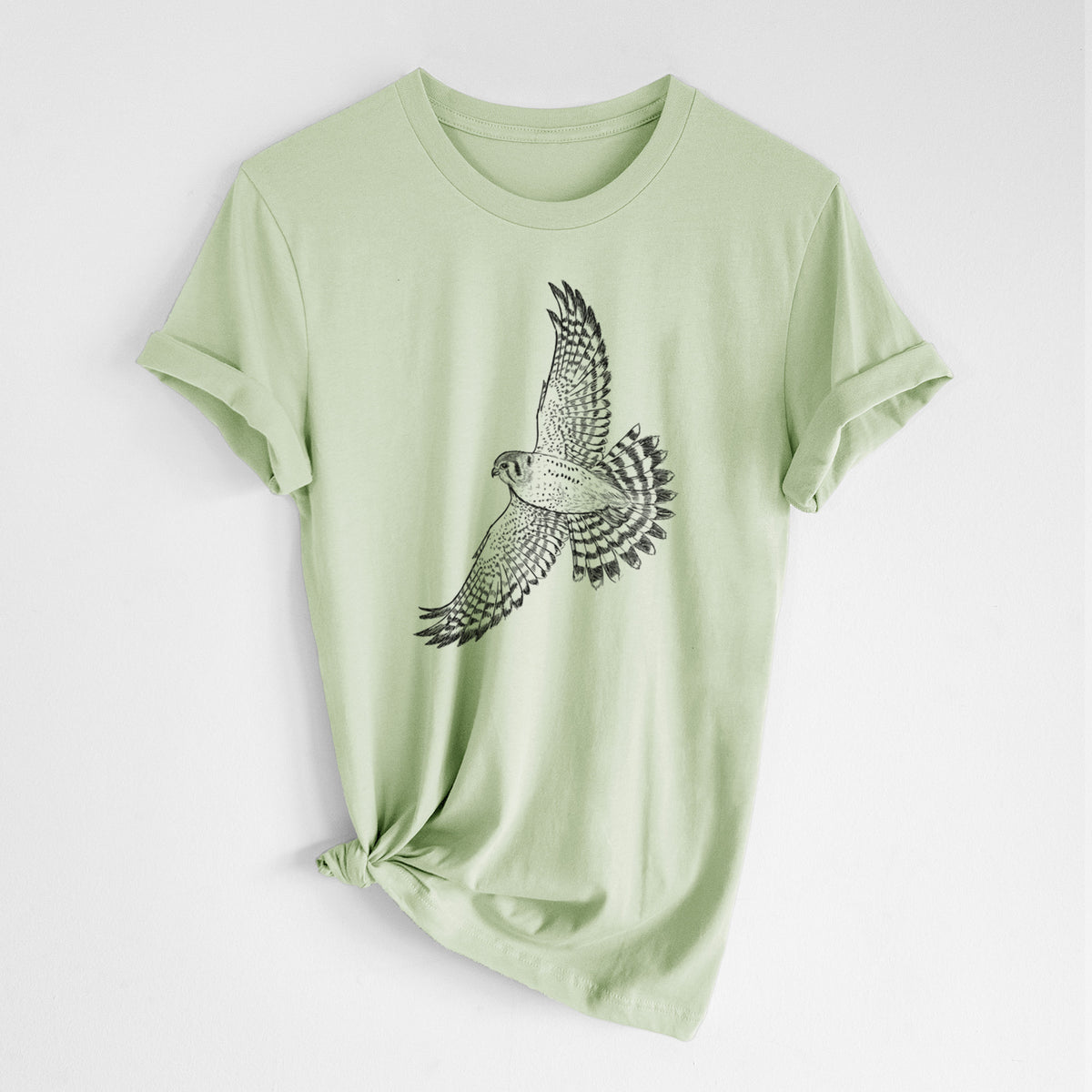 Spring green lightweight cotton t-shirt laid flat with the sleeves rolled, printed with a detailed black ink illustration of an American kestrel in flight with its wings raised.