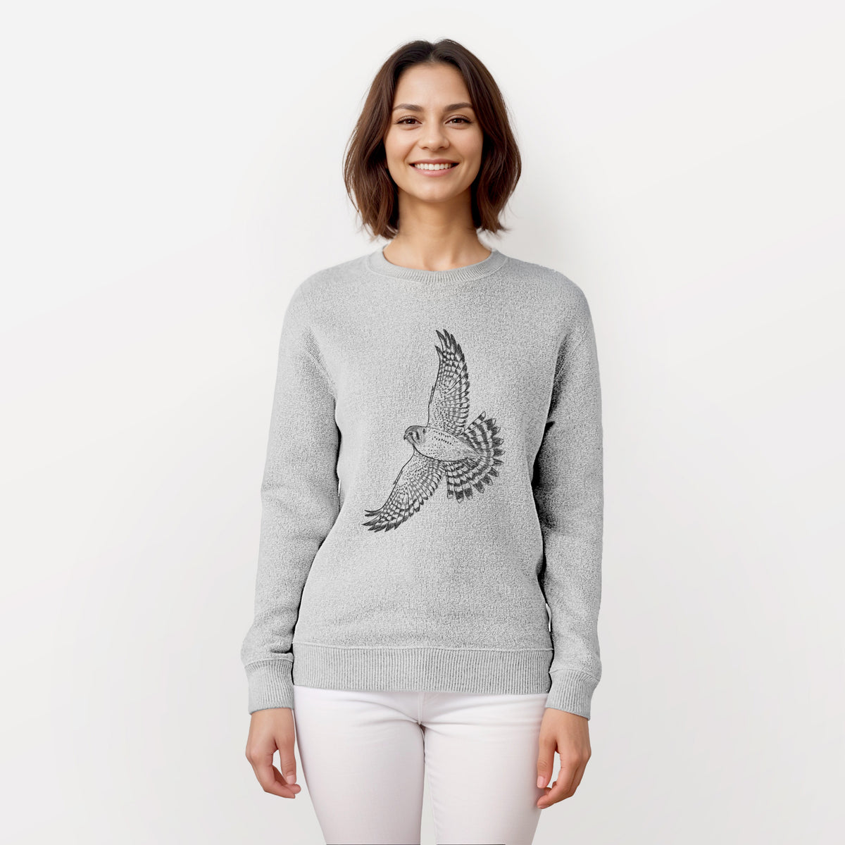 Woman wearing a knit sweatshirt printed with a detailed black ink illustration of an American kestrel in flight with its wings raised.