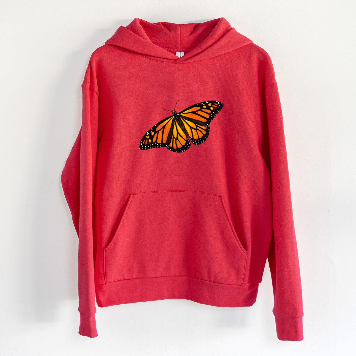 Vibrant Monarch - Danaus plexippus - Statement Midweight Hoodie in Cherry Red, hanging on a white wall, with a front kangaroo pocket and no drawcords.