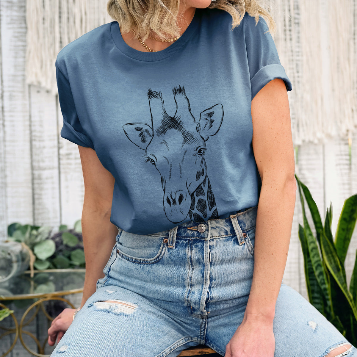 Woman wearing a steel blue lightweight cotton t-shirt printed with a black ink portrait of a southern giraffe's head and neck.