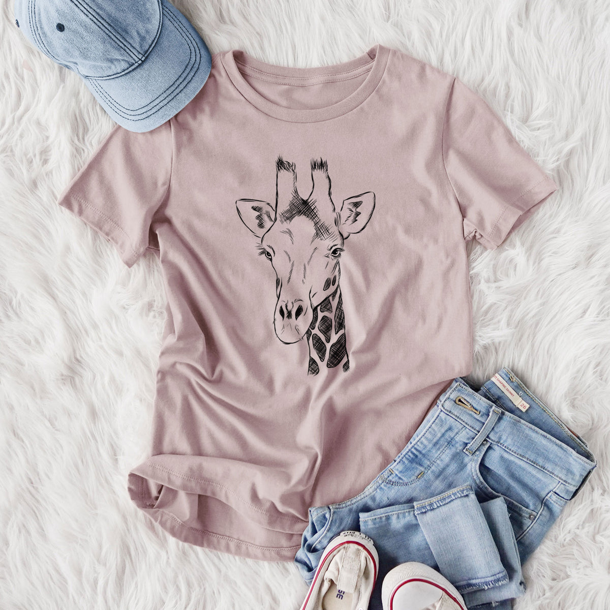 Women's relaxed fit cotton t-shirt printed with a black ink portrait of a southern giraffe's head and neck, styled flat on a white faux fur rug with jeans.