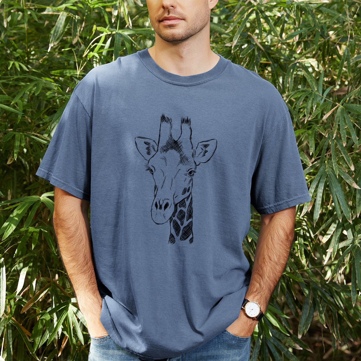 Man wearing a Comfort Colors t-shirt printed with a black ink portrait of a southern giraffe's head and neck, outdoors.