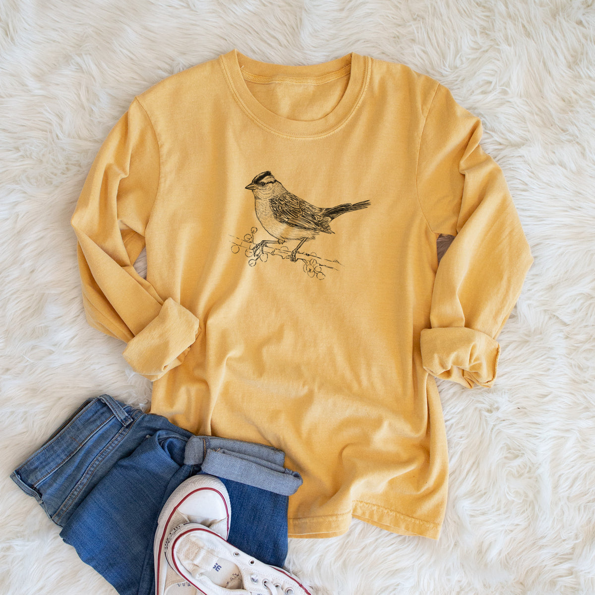 Golden wheat yellow Comfort Colors long sleeve shirt printed with a detailed black ink sketch of a white-crowned sparrow perched on a branch, shown in a lifestyle photo.