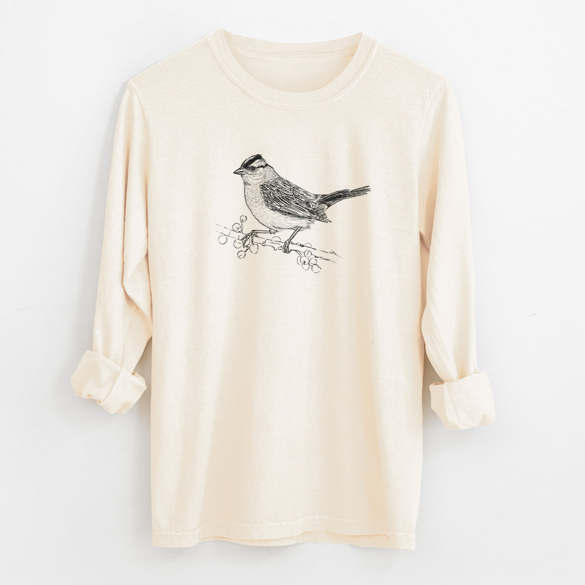 Ivory Comfort Colors long sleeve shirt laid flat with the cuffs rolled, printed with a detailed black ink sketch of a white-crowned sparrow perched on a branch.
