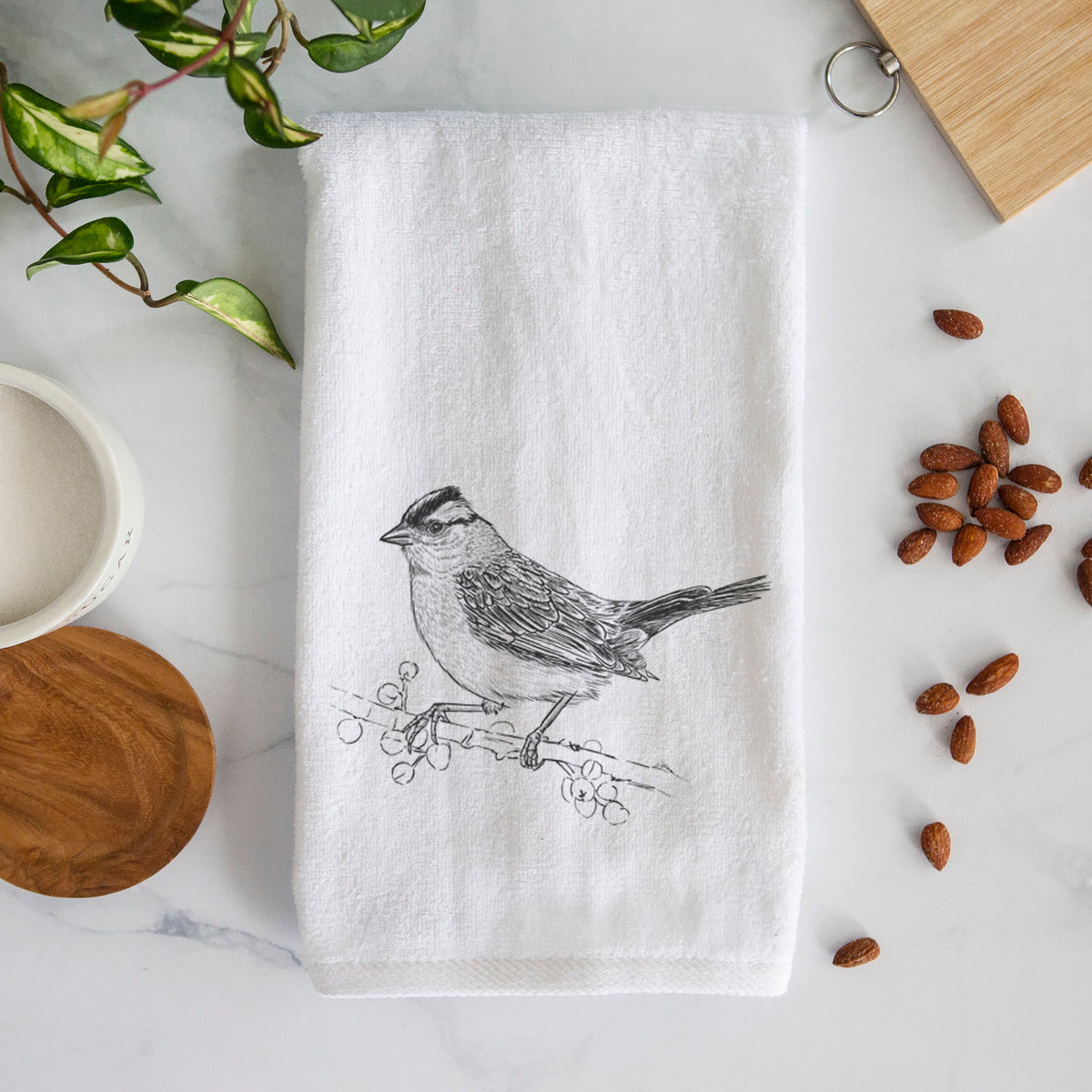 White hand towel printed with a detailed black ink sketch of a white-crowned sparrow perched on a branch.