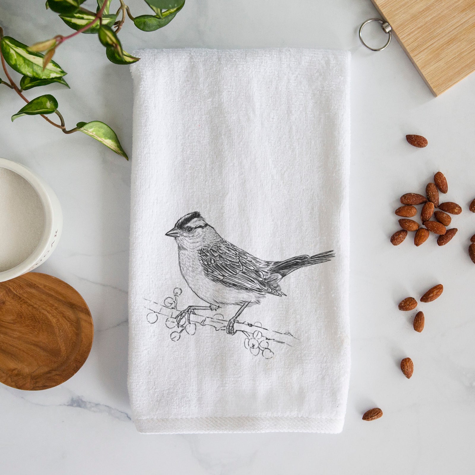 White hand towel printed with a detailed black ink sketch of a white-crowned sparrow perched on a branch.