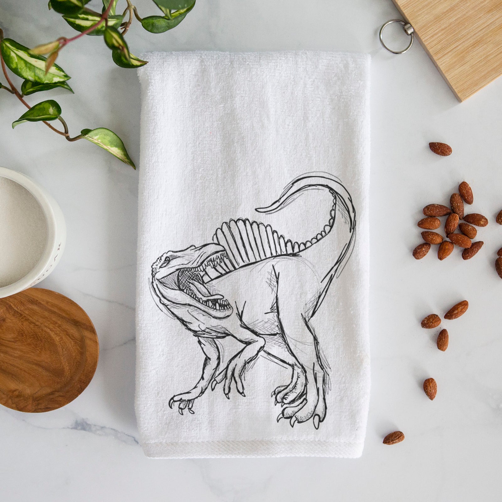 White hand towel printed with a black ink illustration of a Spinosaurus with its tall sail-shaped back.