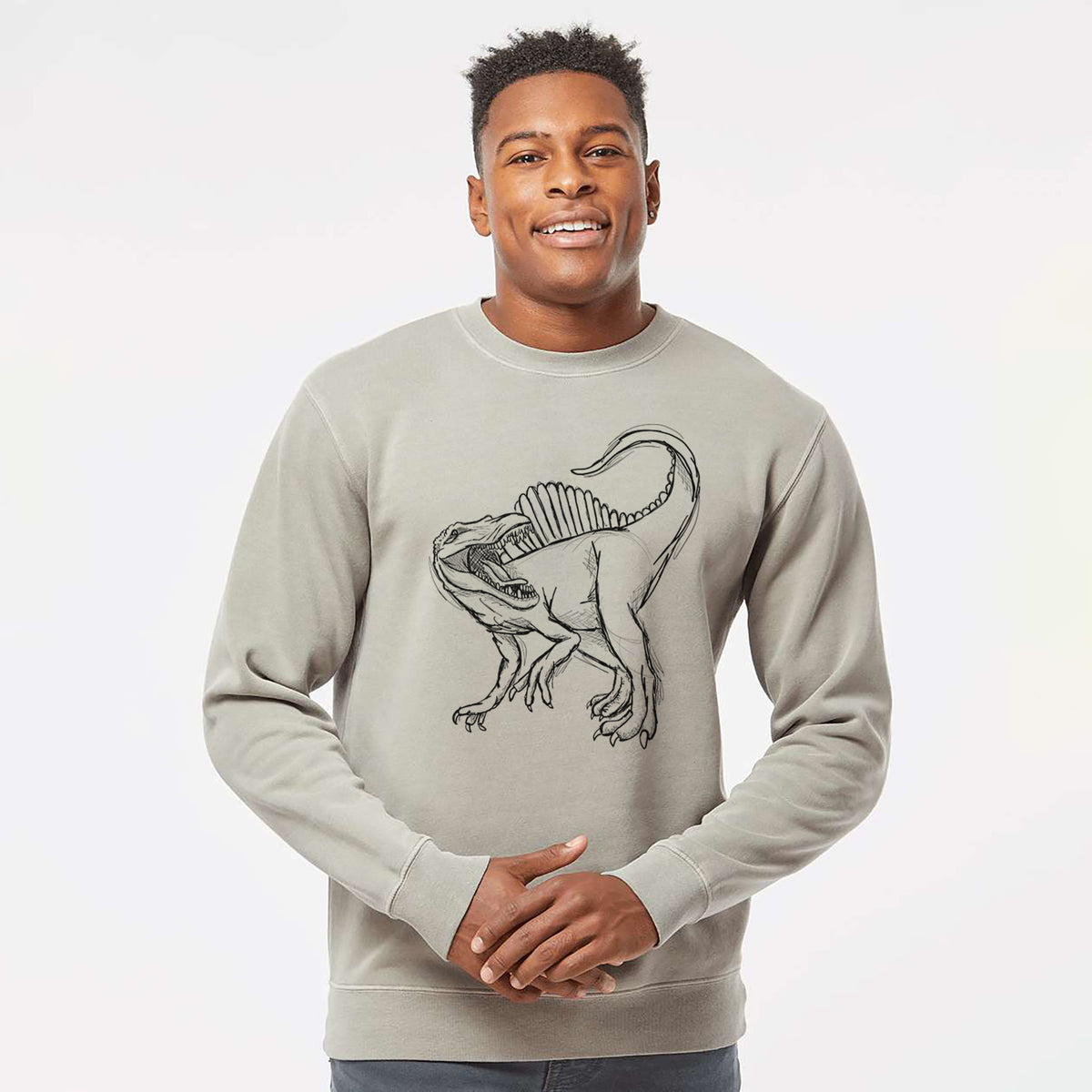 Model wearing a cement grey pigment dyed crewneck sweatshirt printed with a black ink illustration of a Spinosaurus with its tall sail-shaped back.