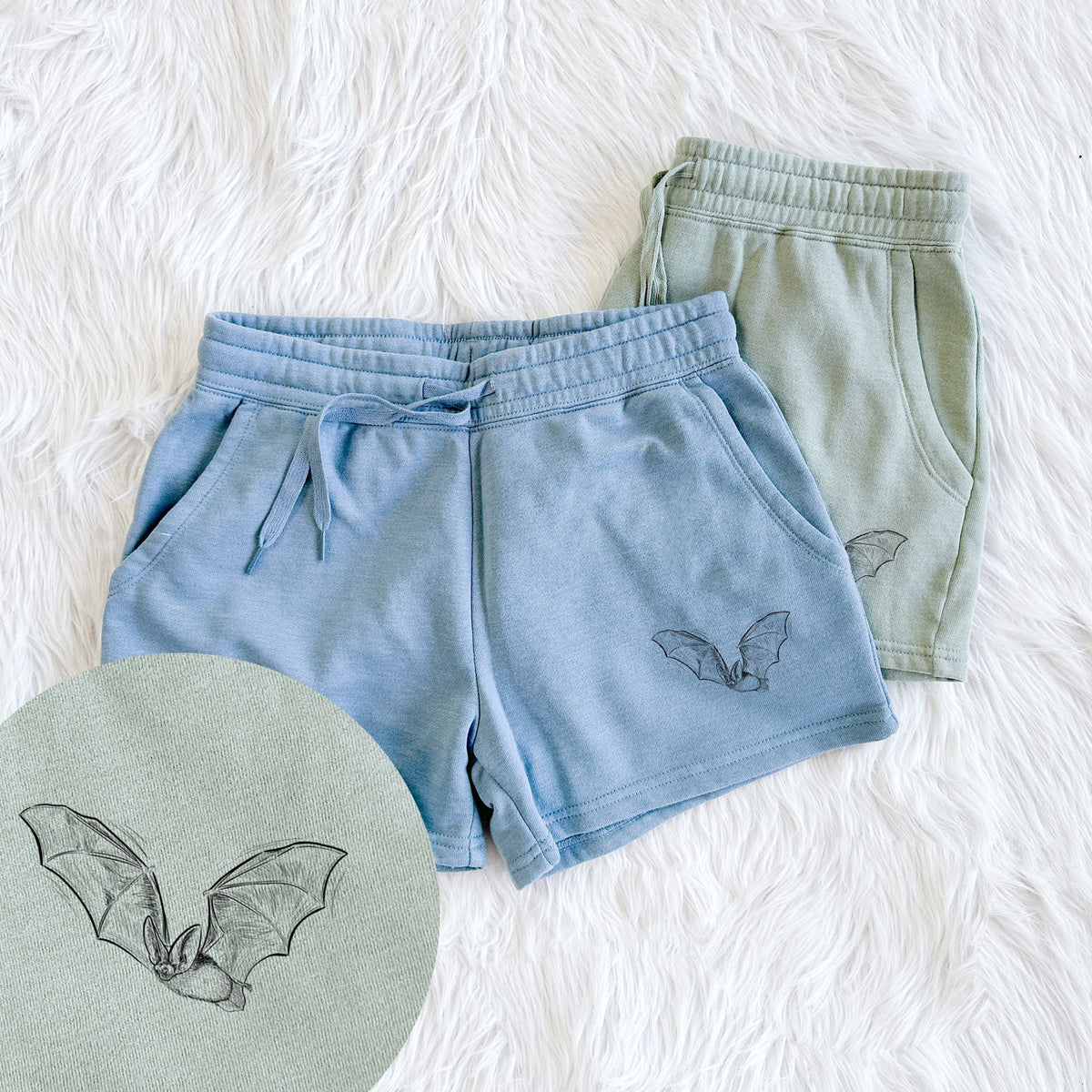 Two pairs of Cali Wave shorts in different colors printed with a black ink illustration of a spotted bat in flight with large ears, with a close-up of the print.