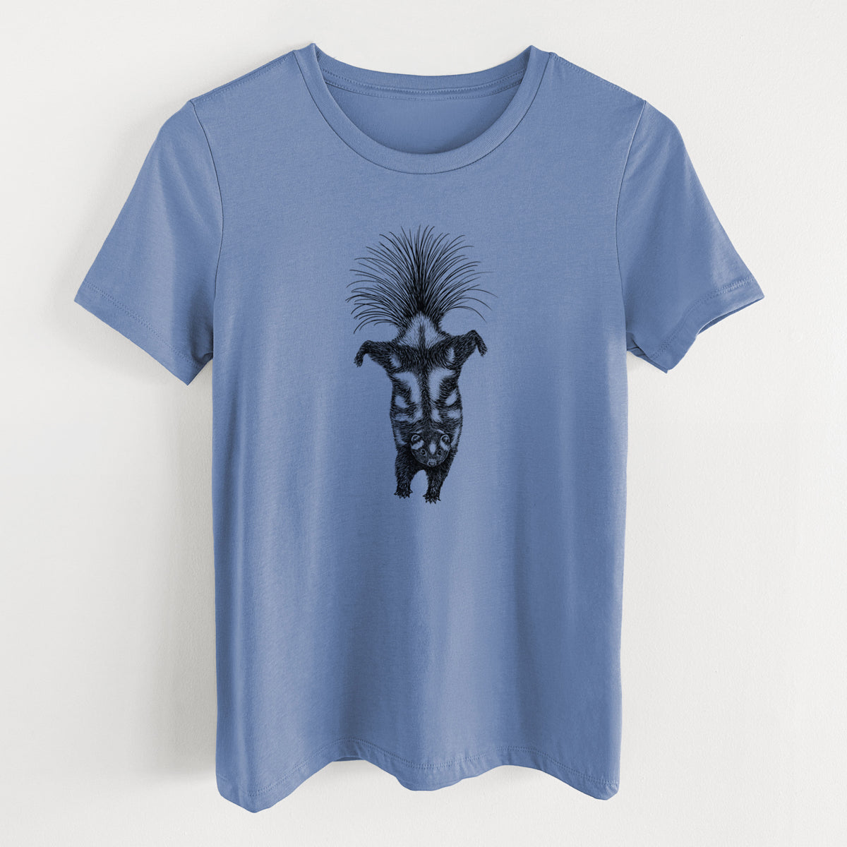 Blue bell women's relaxed fit cotton t-shirt laid flat, printed with a black ink illustration of a spotted skunk doing a handstand with its tail fanned.