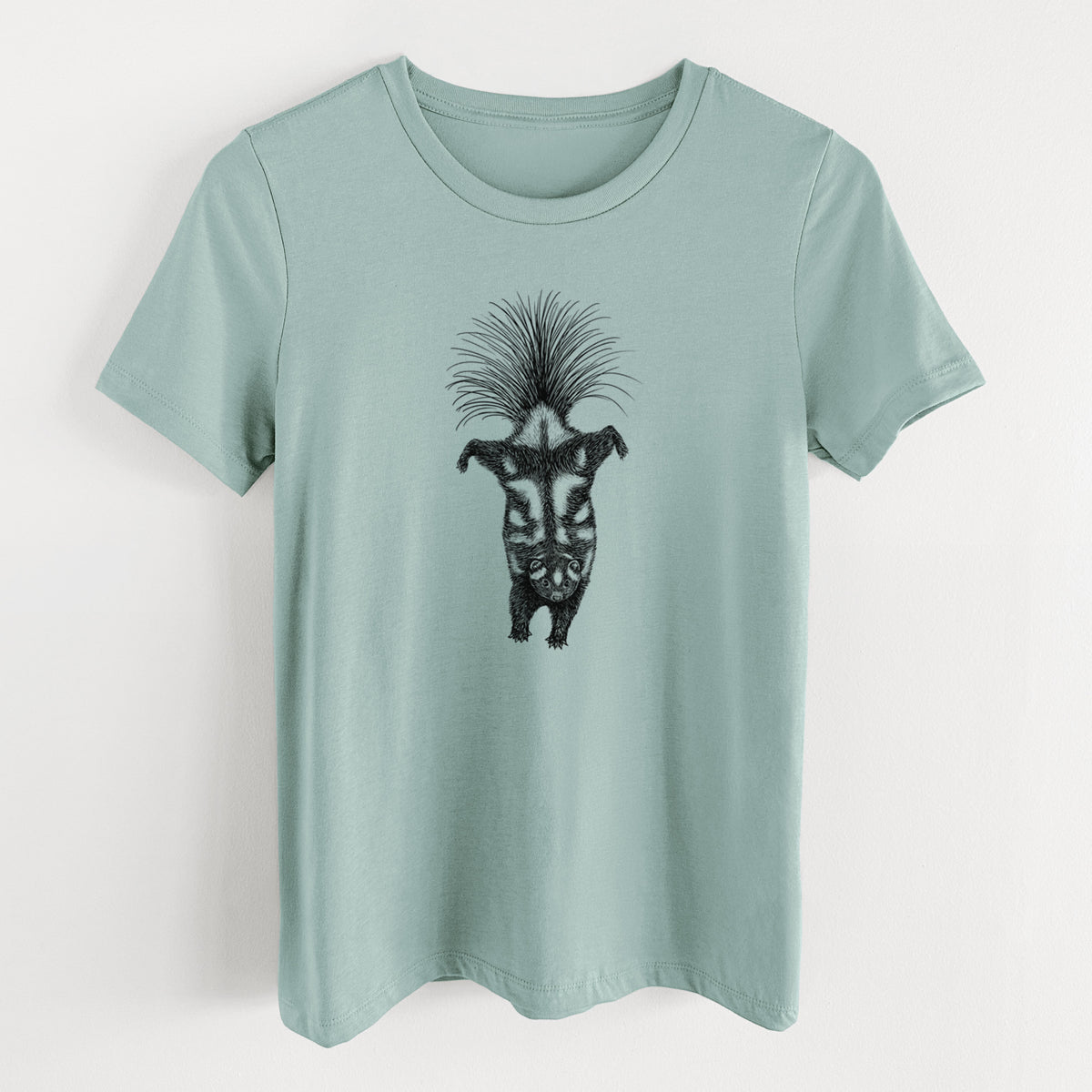 Dusty blue women's relaxed fit cotton t-shirt laid flat, printed with a black ink illustration of a spotted skunk doing a handstand with its tail fanned.