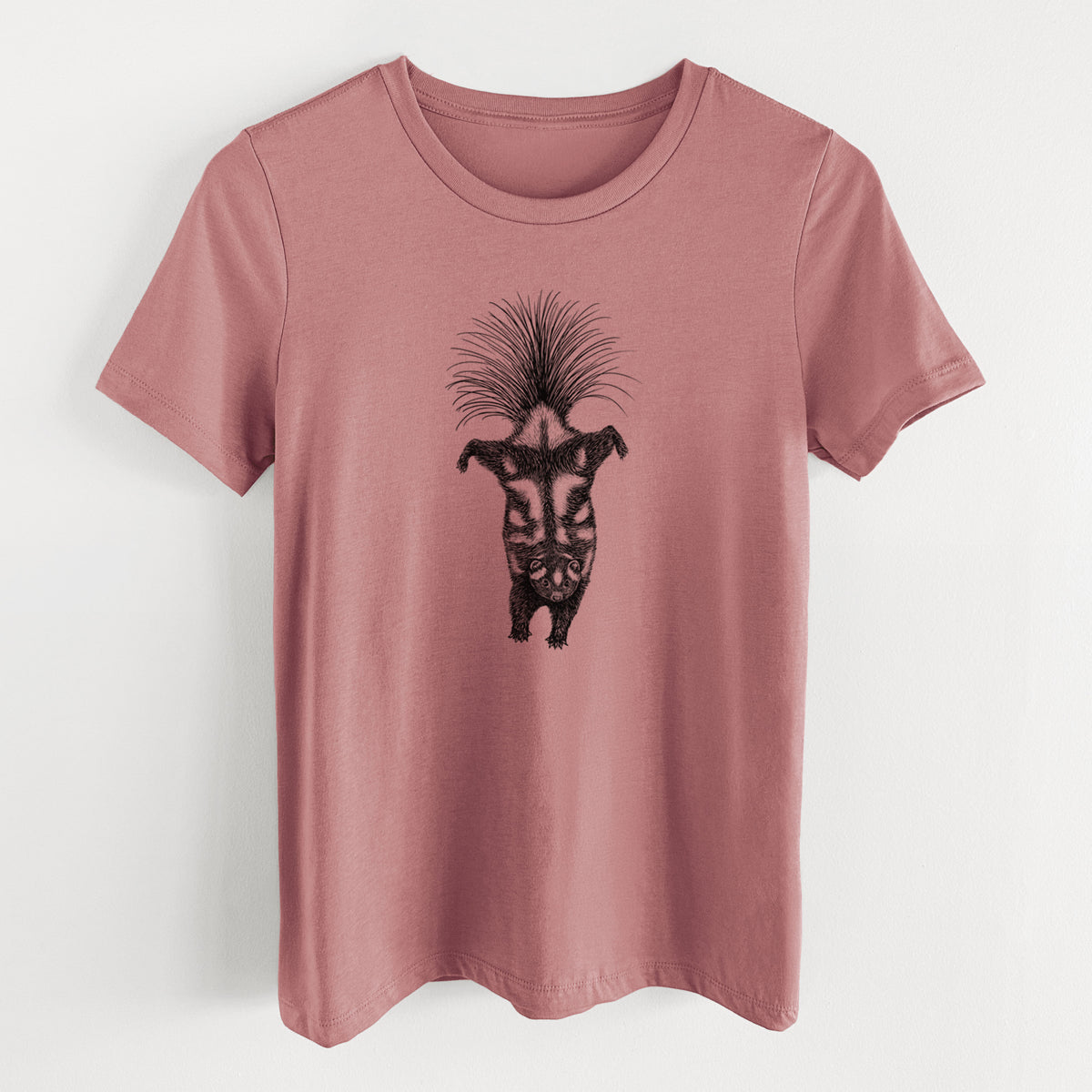 Mauve pink women's relaxed fit cotton t-shirt laid flat, printed with a black ink illustration of a spotted skunk doing a handstand with its tail fanned.