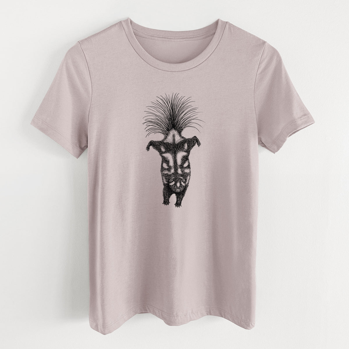 Pink gravel women's relaxed fit cotton t-shirt laid flat, printed with a black ink illustration of a spotted skunk doing a handstand with its tail fanned.
