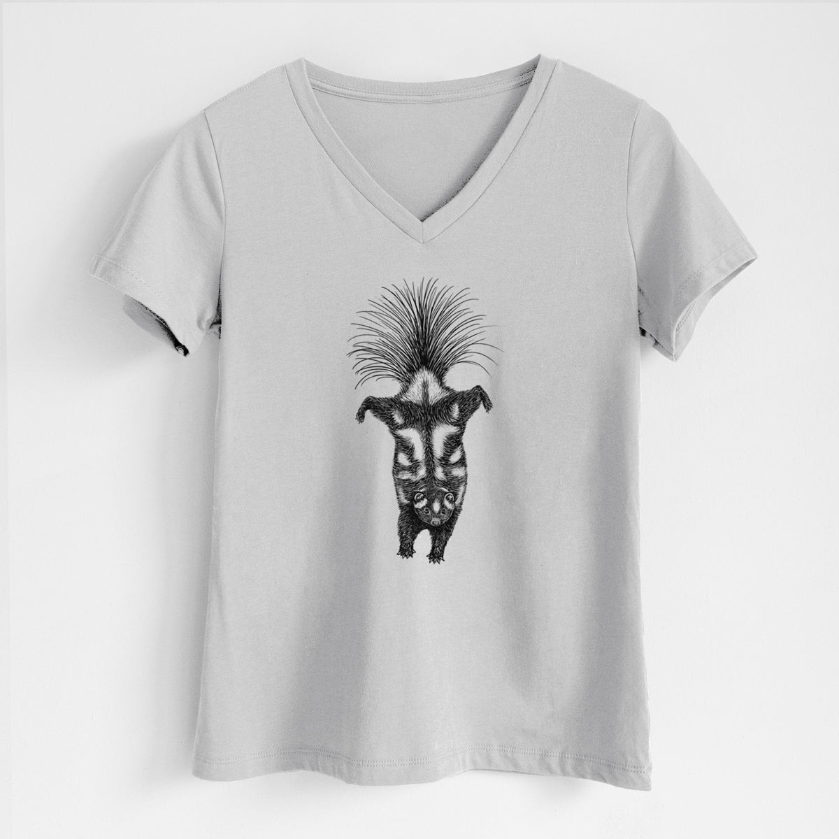 Lunar grey women's relaxed fit cotton V-neck t-shirt laid flat, printed with a black ink illustration of a spotted skunk doing a handstand with its tail fanned.