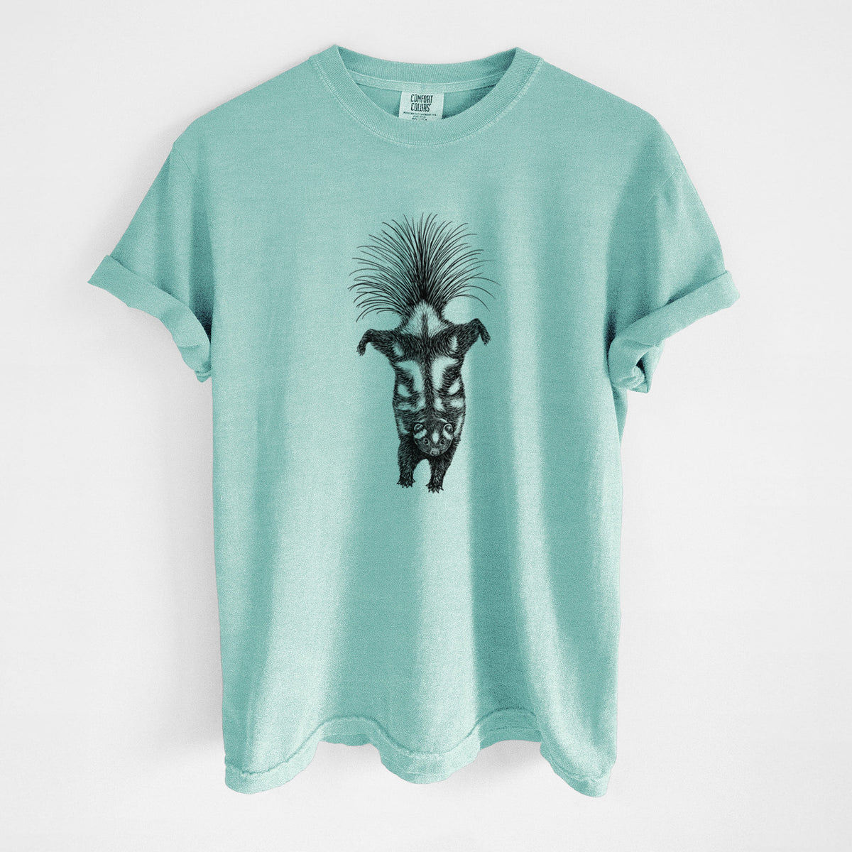 Chalky mint Comfort Colors t-shirt laid flat, printed with a black ink illustration of a spotted skunk doing a handstand with its tail fanned.