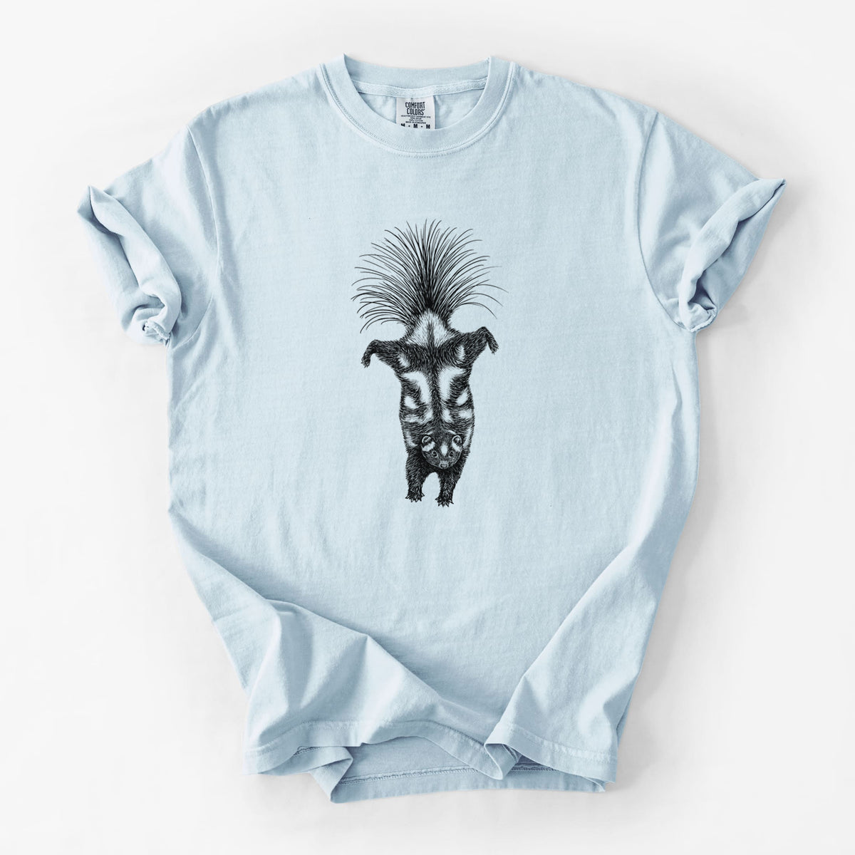 Chambray blue Comfort Colors t-shirt laid flat, printed with a black ink illustration of a spotted skunk doing a handstand with its tail fanned.